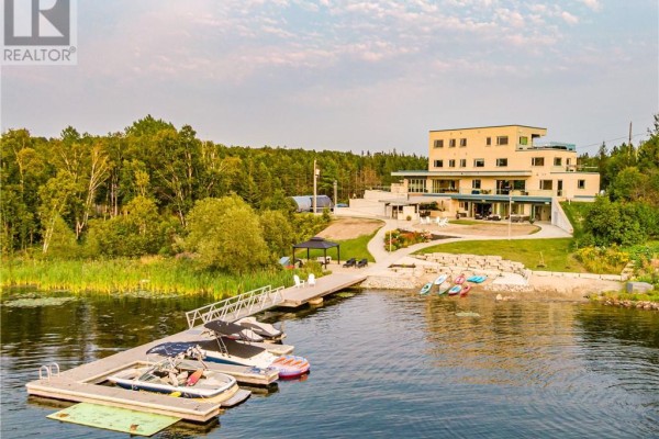 Close-up of the dock with boats and kayaks, leading to the modern home. - 2410 South Bay Road, Sudbury