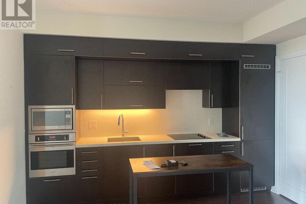 Contemporary kitchen featuring dark cabinetry, stainless steel appliances, and a central island. - 2419 - 5 Sheppard Avenue E, Toronto