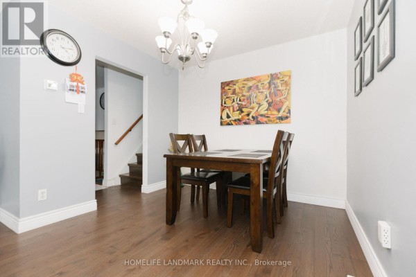 Dining room with a wooden table and chairs, set against light grey walls and a dark wood floor. - 2419 Cashmere Avenue, Mississauga