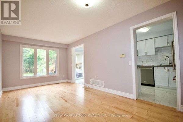 View from the living room looking towards a kitchen with white cabinets and stainless steel appliances. - 2419 Susquehanna Court, Oakville
