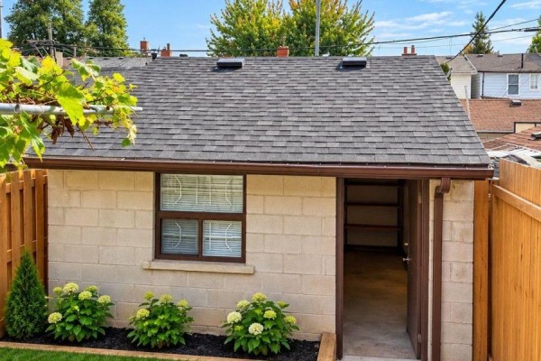 Backyard garage exterior with a small window and an open doorway revealing shelves. - 242 Silverthorn Avenue, Toronto