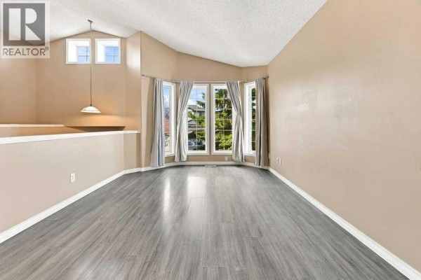 Interior view of a bright living area with a vaulted ceiling and beige walls. - 242 Springs Place Se, Airdrie