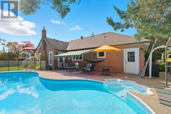 Backyard patio with a kidney-shaped swimming pool, patio furniture, and an awning. - 242 Stephenson Point Road, Scugog