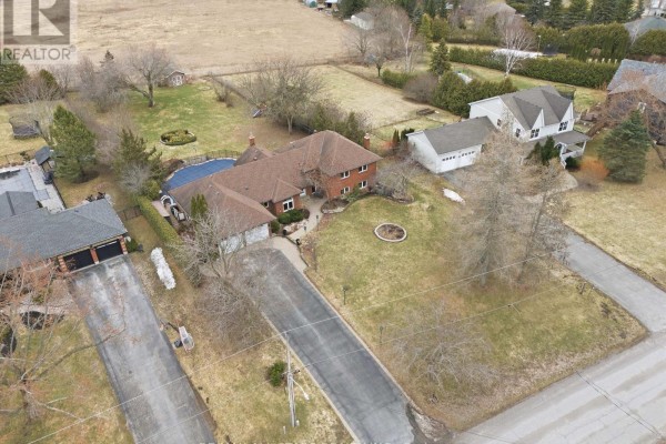 Aerial view of a brick house with a circular driveway, pool, and surrounding properties. - 242 Stephenson Point Road, Scugog