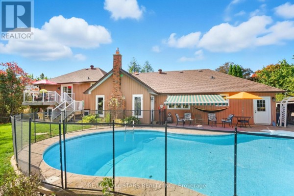 Kidney-shaped swimming pool in the backyard with patio furniture and a fenced yard. - 242 Stephenson Point Road, Scugog