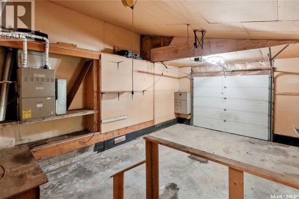 Interior view of a garage with a furnace, unfinished walls, concrete floor, and garage door. - 242 Woodlawn Avenue, Katepwa Beach