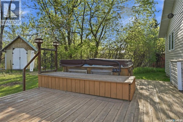 Wooden deck with an outdoor hot tub and a small storage shed in the background. - 242 Woodlawn Avenue, Katepwa Beach