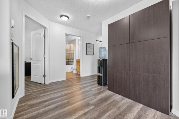 Hallway with a water cooler and storage cabinets, showing doorways to bedrooms and bathroom. - #2420 320 Clareview Station Dr Nw, Edmonton