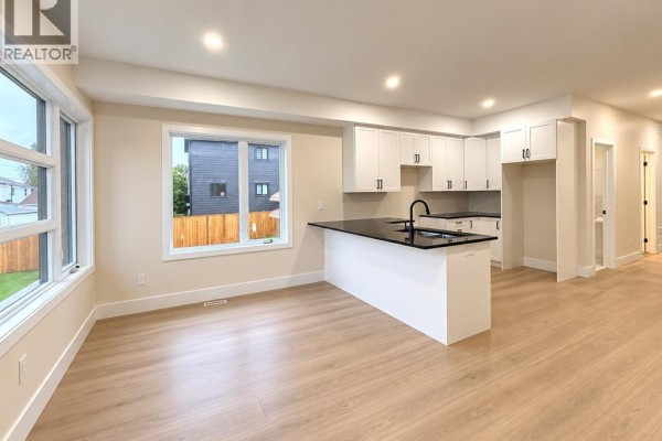 Open-concept living and kitchen area with light wood flooring and white cabinets. - 2422 Bernard, Windsor