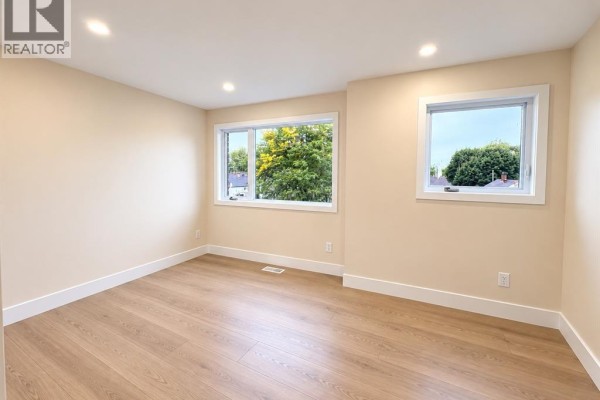 Empty bedroom with light beige walls, two windows, and light wood laminate flooring. - 2422 Bernard, Windsor
