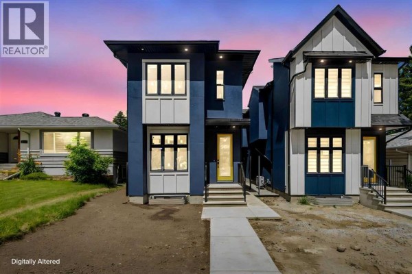Modern blue and white duplex exterior at dusk with yellow front door and large windows. - 2426 25 Avenue Nw, Calgary