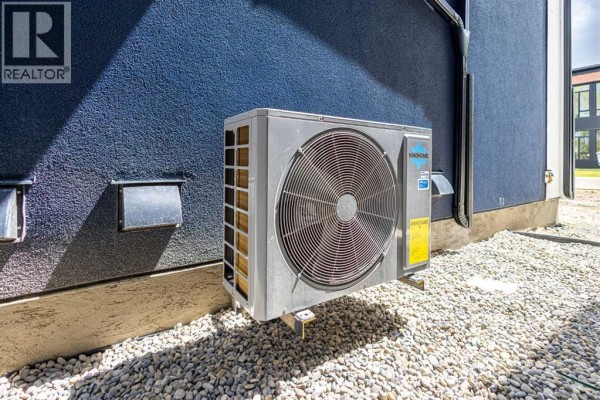 Exterior shot of an air conditioning unit mounted on a textured blue wall. - 2426 25 Avenue Nw, Calgary