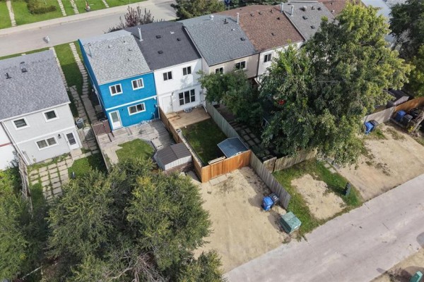 Aerial view of the backyards of townhouses, showing small yards, wooden fences, and sheds. - 243 Houde Drive, Winnipeg