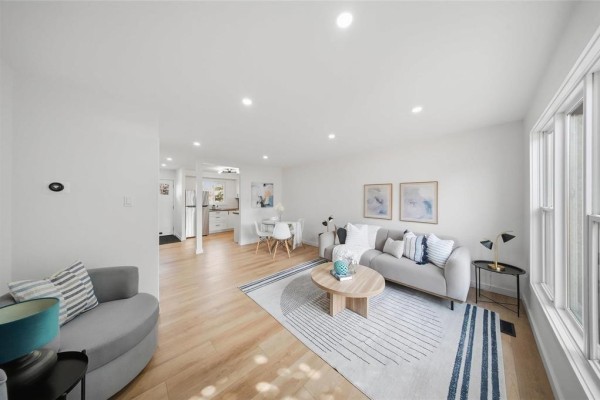 Living room with white walls, wood floors, a sofa, coffee table, and dining area. - 243 Houde Drive, Winnipeg