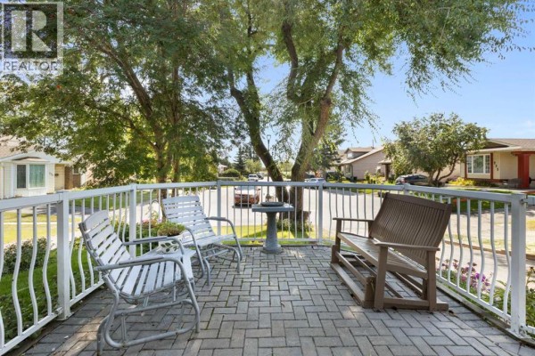 View of the covered porch with seating area, overlooking the street and neighborhood. - 243 Radcliffe Place Se, Calgary