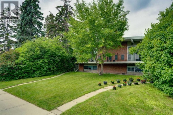 Side view of the brick duplex showing the sloped lawn and pathway leading to the entrance. - 2431 & 2429 26 Street Sw, Calgary