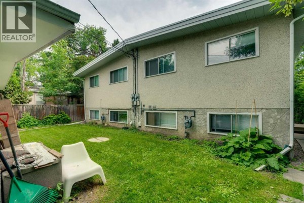 Back view of the duplex with stucco siding, concrete foundation, and multiple windows on both levels. - 2431 & 2429 26 Street Sw, Calgary