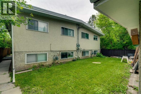 Another angle of the rear of the duplex, highlighting the lawn and surrounding trees. - 2431 & 2429 26 Street Sw, Calgary