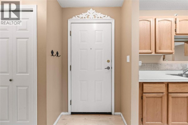 Interior view of the front entrance with a white door, closet, and oak cabinetry. - 2435 Pleasant Valley Road Unit# 206, Armstrong
