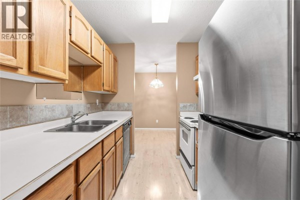 Kitchen with light wood cabinets, white countertops, stainless steel refrigerator, and stove. - 2435 Pleasant Valley Road Unit# 206, Armstrong