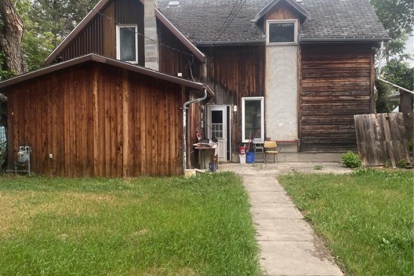 Rear exterior of a house with wooden siding and a concrete walkway. - 244 Hudson Avenue S, Fort Qu Appelle