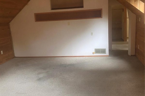 Empty room with beige carpet, white walls, and wood trim under a sloped ceiling. - 244 Hudson Avenue S, Fort Qu Appelle