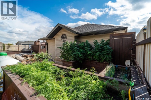 Backyard garden with raised wooden beds containing vegetables and a fence. - 244 Moose Road, Crooked Lake
