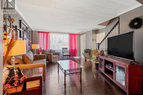 Living room with grey sofa, dark wood floors, and dining room view through archway. - 244 North Street, Fort Erie