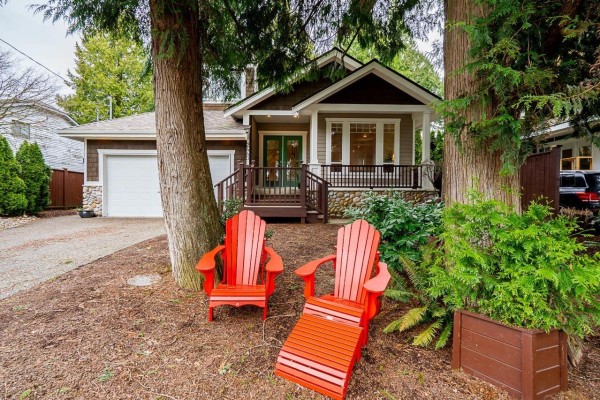 Bedroom with a wooden bed frame, white bedding, dresser, two windows, and a patterned rug. - 2440 124b Street, Surrey