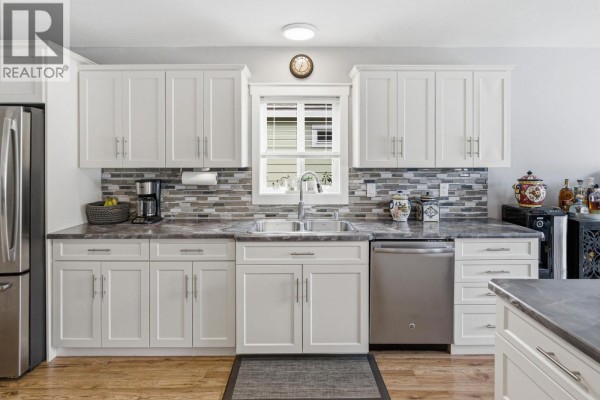 Kitchen with white cabinetry, an island with bar stools, and stainless steel appliances. - 2440 Old Okanagan Highway Unit# 523, West Kelowna