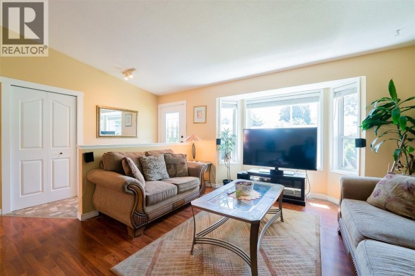 Kitchen with white cabinets, stainless steel appliances, and doorway to dining room. - 2446 Divot Dr, Nanaimo
