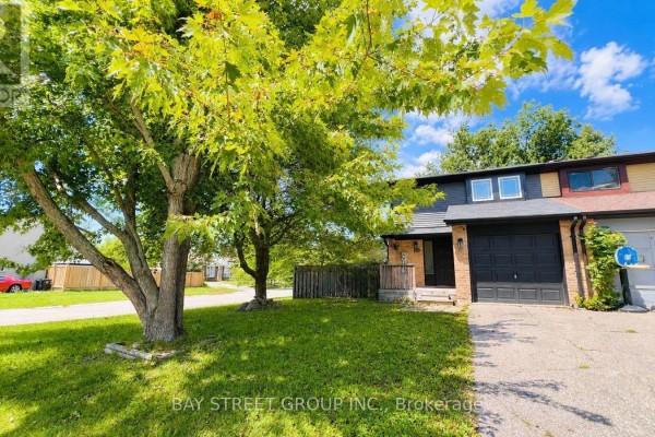 View of the townhouse entrance and garage with a large tree to the left. - 245 Browning Trail, Barrie