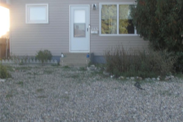 Close-up of the beige vinyl siding and front door of the house. - 245 Edward Street, Regina