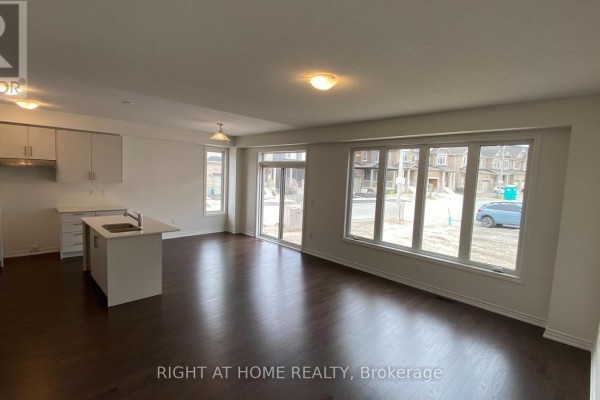 An open-concept living space with a kitchen island, large windows, and a sliding door. - 245 Madelaine Drive, Barrie