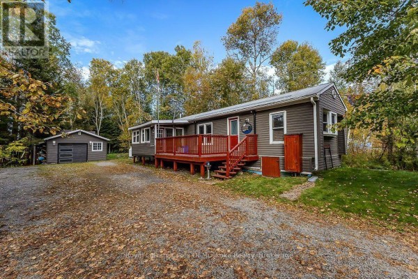 Grey vinyl-sided bungalow with a detached garage and a red wooden deck. - 245 Main Street, Kearney