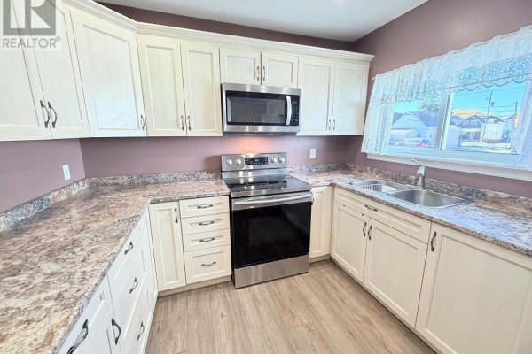 U-shaped kitchen with white cabinets, granite countertops, stainless steel appliances, and a window. - 245 Maple Street S, Timmins