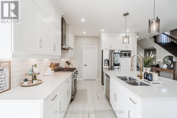 Modern white kitchen with island, gold faucet, and stainless steel appliances - 245 Tamarack Boulevard Woodstock