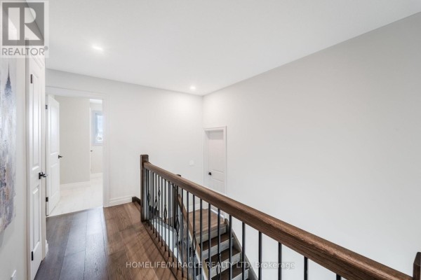 Hallway with hardwood floors, staircase, and wooden handrail - 245 Tamarack Boulevard Woodstock