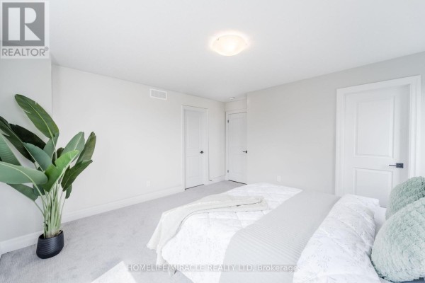 Bedroom with large plant and white bedding - 245 Tamarack Boulevard Woodstock