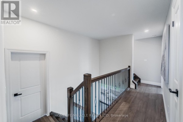 Hallway with hardwood floors, wood banister, and wrought iron spindles - 245 Tamarack Boulevard Woodstock