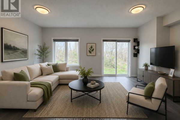 Living room with dark wood laminate flooring, grey walls, and large windows overlooking a backyard. - 245 Wesley Boulevard, Cambridge