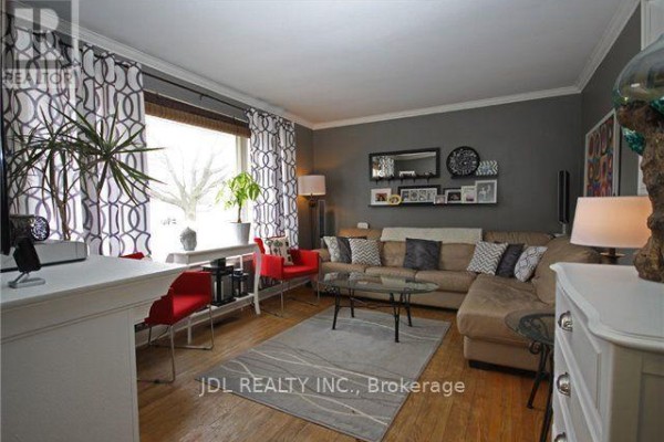 Living room with a large sectional sofa, glass coffee table, patterned curtains, and red accent chairs. - 245 Windsor Street, Oshawa