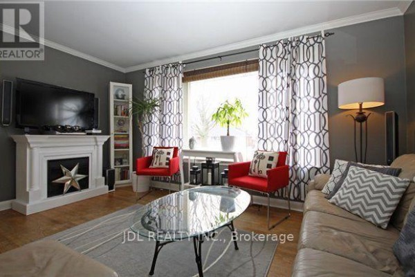 Living room with a fireplace, television, bookshelf, patterned curtains, red chairs, and a glass coffee table. - 245 Windsor Street, Oshawa