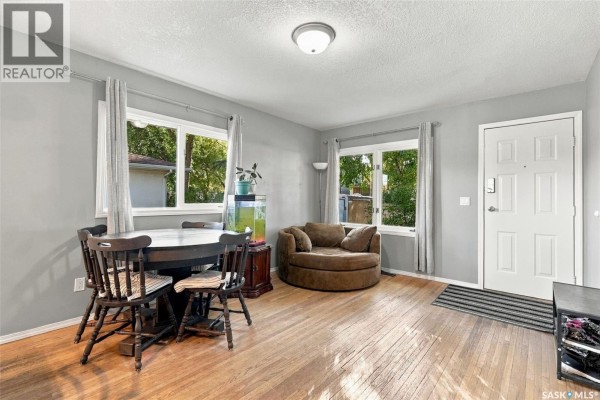 Living and dining room with hardwood floors, grey walls, a round table and chairs. - 2451 Francis Street, Regina