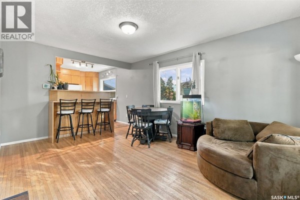 Open concept living area with dining table and kitchen pass-through with bar stools. - 2451 Francis Street, Regina