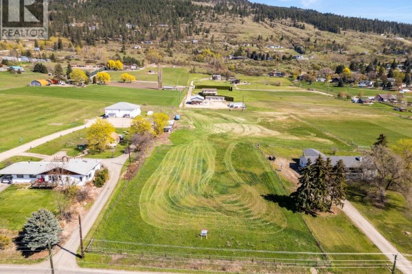 Aerial view looking across a large, grassy property with a winding mowed path and surrounding residences. - 2455 East Vernon Road, Vernon