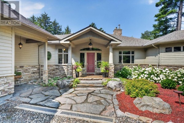Close-up of the front entrance of a house with a stone foundation, beige siding, and a stone walkway. - 2458 Wilkinson Road, Dysart Et Al