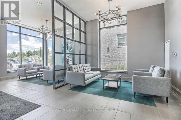 Modern building lobby with gray sofas, glass partitions, and large windows. - 246 - 555 William Graham Drive, Aurora