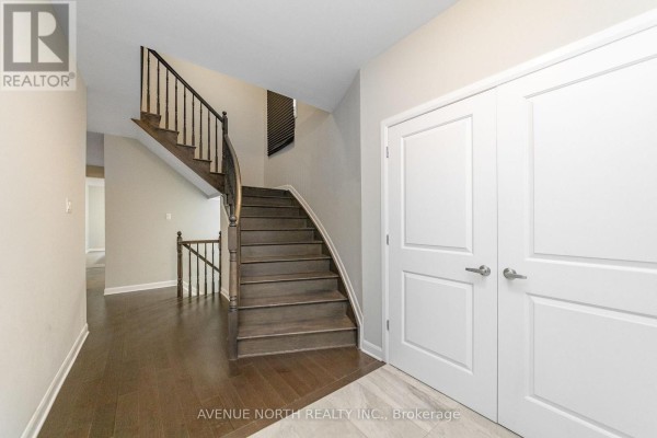 Entrance hall with hardwood floors, a carpeted staircase with dark wood treads and black railing. - 246 Aquarium Avenue, Ottawa