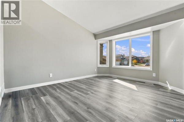 View from upstairs overlooking a staircase with dark wood railings and white doors below. - 246 Sutter Place, Saskatoon